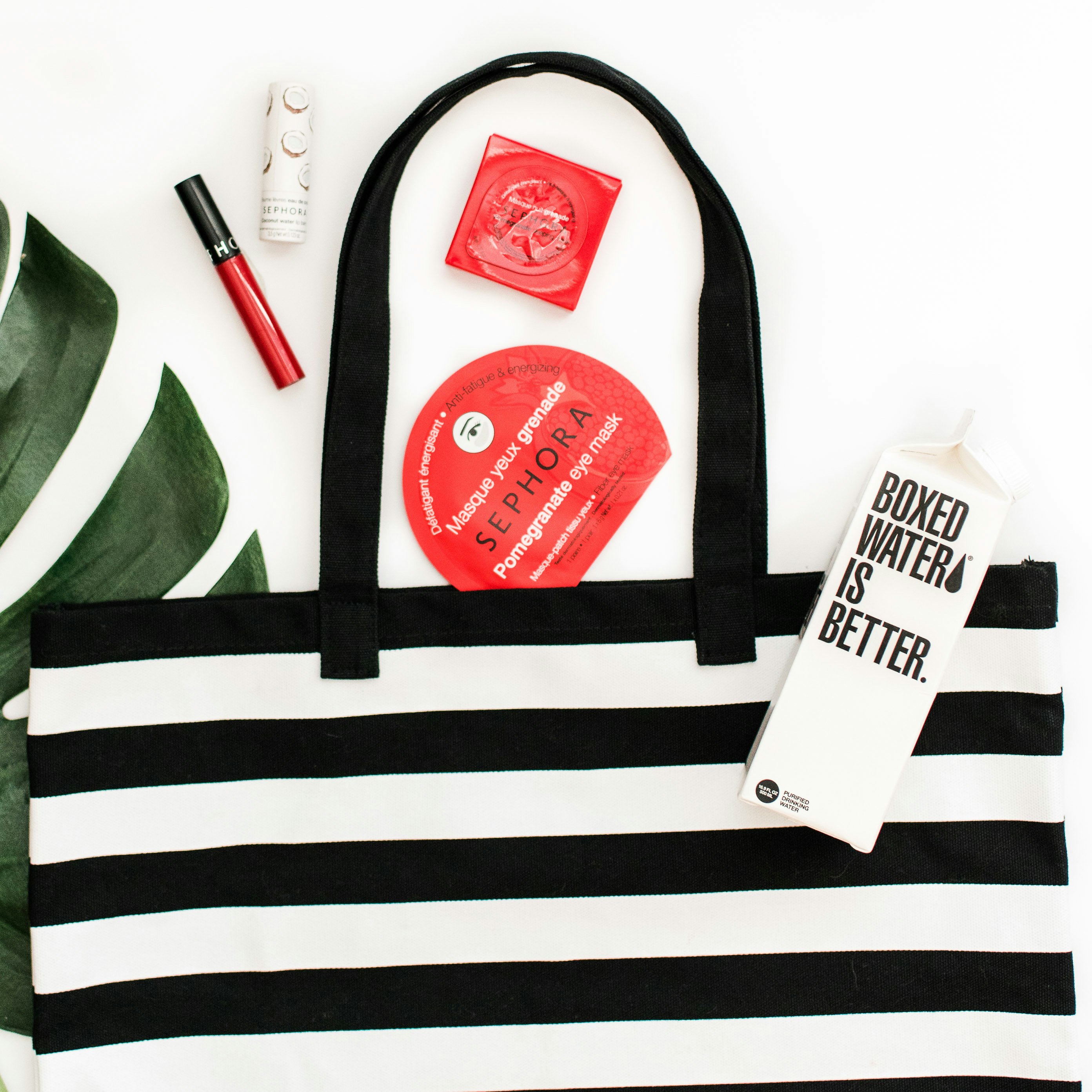 A black and white striped handbag with Sephora and Boxed Water products displayed next to it